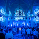 Mitglieder der Gemeinde Neues Leben Kirche in Aachen arbeiten an der Steuerung von Licht und Ton während eines Gottesdienstes. Sie konzentrieren sich darauf, eine einladende und inspirierende Atmosphäre zu schaffen.