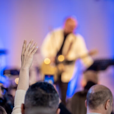 Gemeindemitglieder der Freikirche Neues Leben in Aachen erheben ihre Hände und singen gemeinsam während einer Lobpreiszeit.