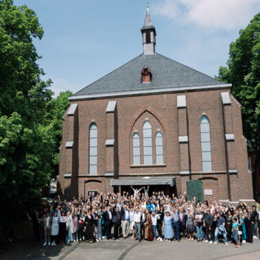 Freikirche Neues Leben in Aachen: Gruppe von Menschen steht vor dem Gebäude der Neues Leben Kirche Aachen St.Barbara Aachen Rothe Erde